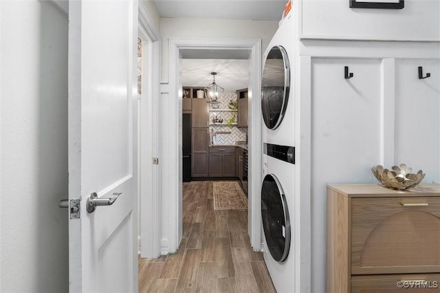 clothes washing area with estacked washer and dryer and light wood-style floors