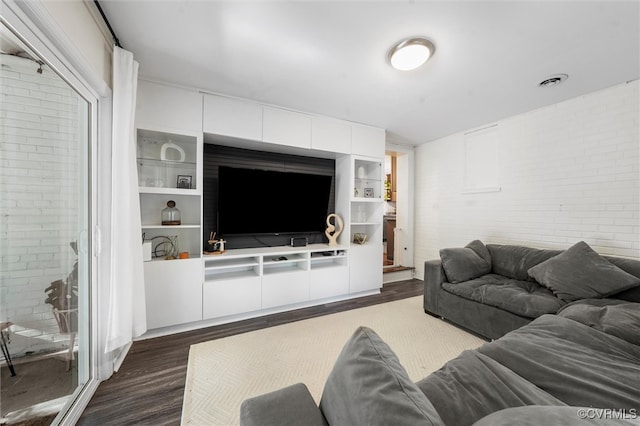living area with brick wall and dark wood-style flooring