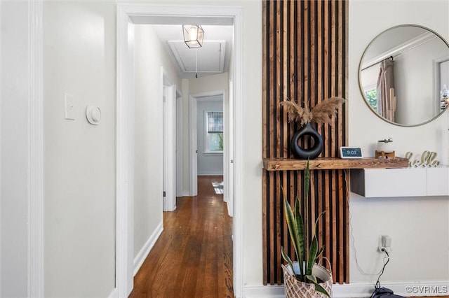 corridor with attic access, wood finished floors, and baseboards