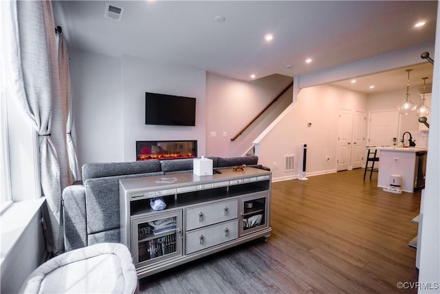 living room with dark wood-style floors, recessed lighting, stairway, a glass covered fireplace, and baseboards
