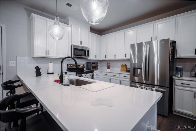kitchen with stainless steel appliances, a sink, light countertops, white cabinets, and a peninsula