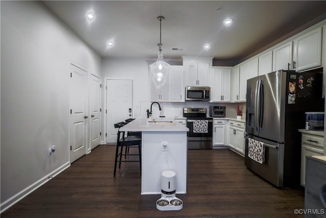 kitchen with stainless steel appliances, a sink, dark wood-type flooring, light countertops, and recessed lighting