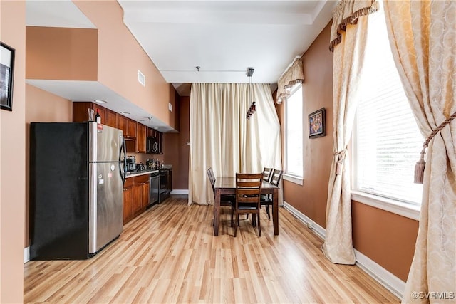 kitchen featuring freestanding refrigerator, brown cabinetry, light wood-style flooring, and baseboards