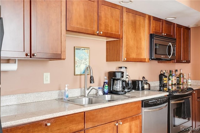 kitchen with appliances with stainless steel finishes, a sink, and brown cabinetry