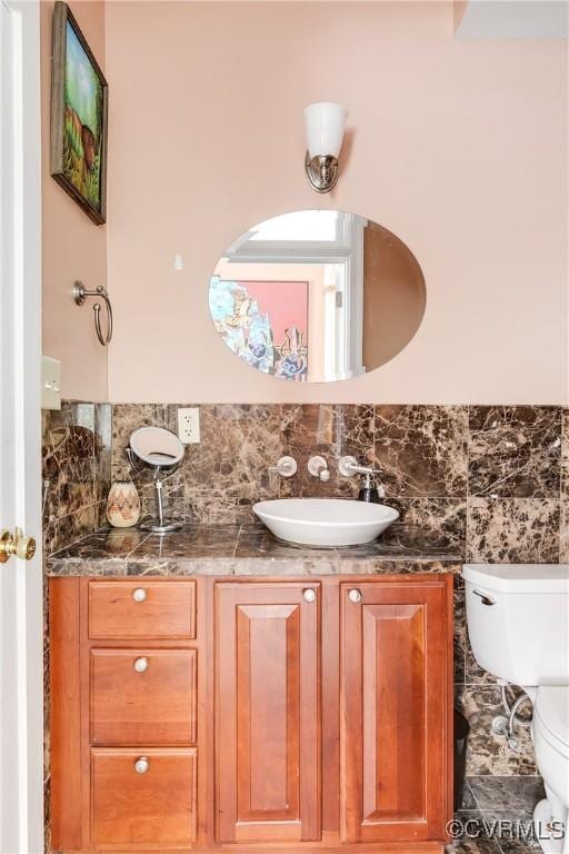 half bathroom with toilet, vanity, and tasteful backsplash