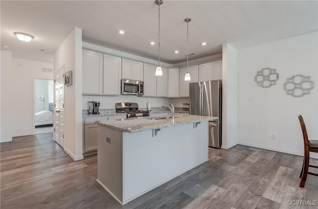 12106 Oxford Landing Dr Unit 202, Glen Allen, VA 23059 - kitchen featuring appliances with stainless steel finishes, a sink, a kitchen bar, an island with sink, and dark wood-style floors