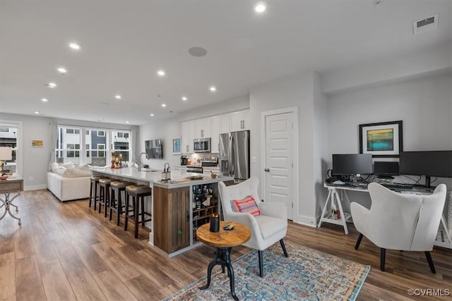 5234 Old Main St Unit C, Henrico, VA 23231 - kitchen featuring appliances with stainless steel finishes, open floor plan, a sink, white cabinetry, and wood finished floors