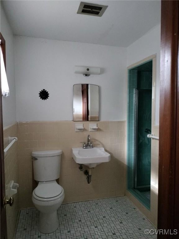 724 Milton Dr, Hampton, VA 23666 - bathroom featuring toilet, tile walls, wainscoting, a stall shower, and a sink