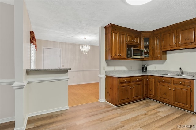 9865 Knobs Hill Ln, Amelia, VA 23002 - kitchen with stainless steel microwave, light wood-style flooring, brown cabinetry, a chandelier, and a textured ceiling