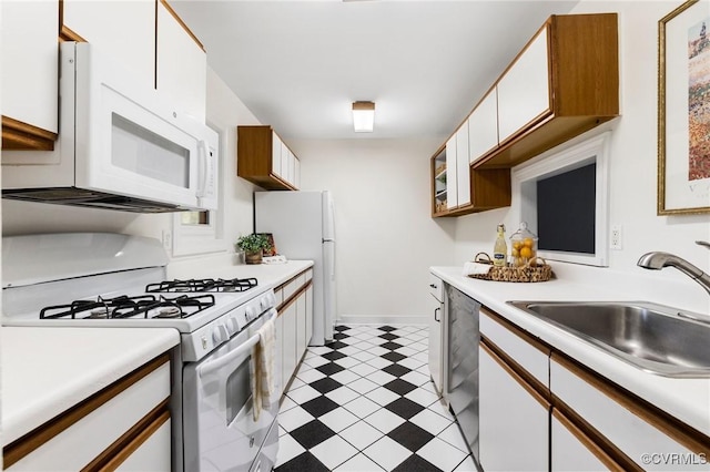 kitchen featuring white appliances, a sink, light flooring, light countertops, and white cabinetry