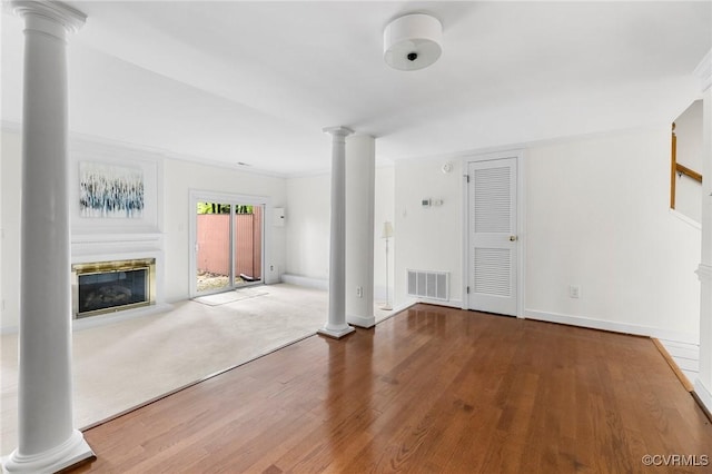 unfurnished living room featuring ornate columns, a glass covered fireplace, wood finished floors, and baseboards