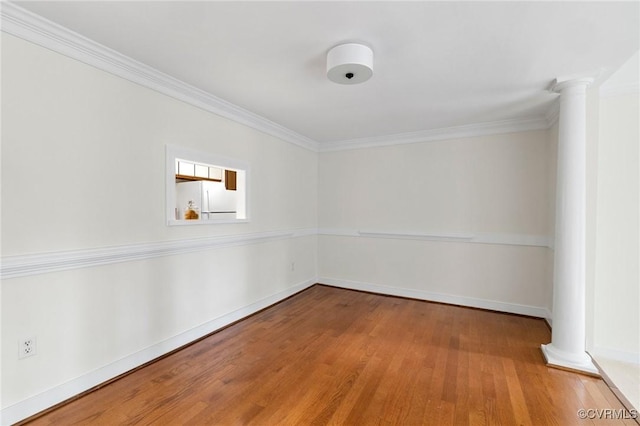 empty room with ornate columns, wood finished floors, ornamental molding, and baseboards