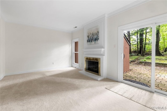 unfurnished living room with carpet flooring, a glass covered fireplace, crown molding, and baseboards