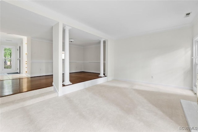 empty room featuring carpet floors, ornate columns, baseboards, and ornamental molding