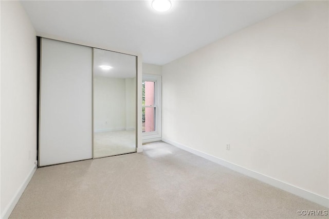 unfurnished bedroom with carpet flooring, baseboards, and a closet