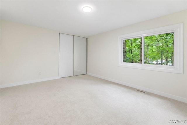 unfurnished bedroom featuring light carpet and baseboards