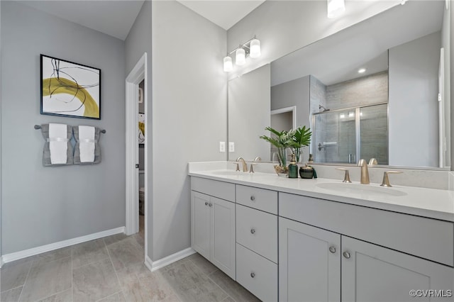 bathroom with a shower stall, double vanity, baseboards, and toilet