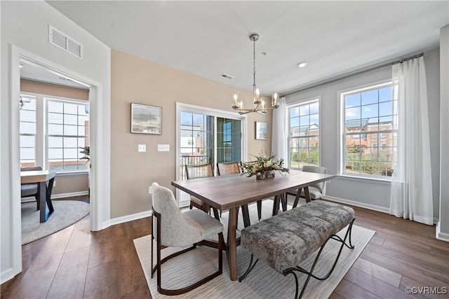 dining room with a chandelier, baseboards, healthy amount of natural light, and dark wood finished floors