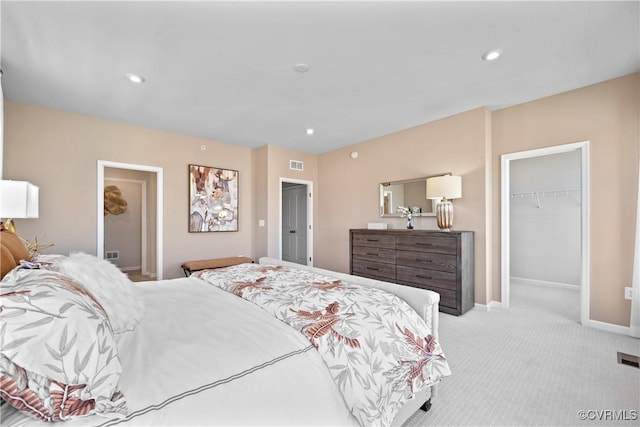 carpeted bedroom with a walk in closet, baseboards, a closet, and recessed lighting