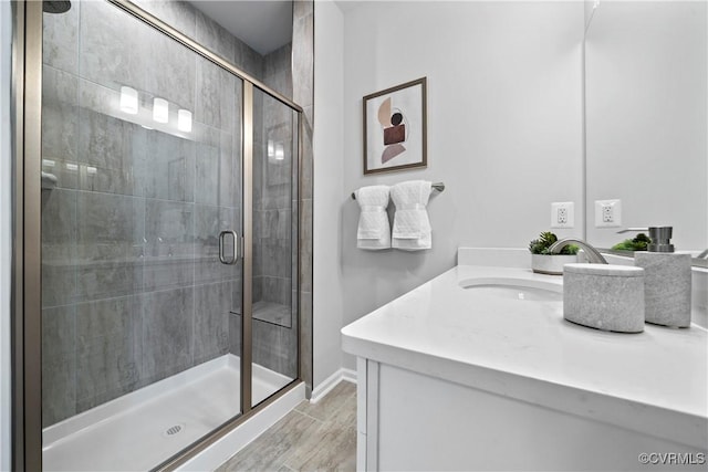 bathroom with a shower stall, vanity, wood finished floors, and baseboards