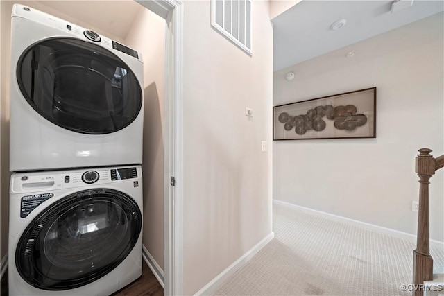 laundry area with stacked washer / drying machine, baseboards, and carpet floors
