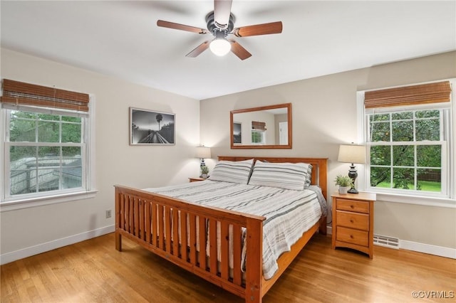 bedroom with multiple windows, baseboards, and wood finished floors