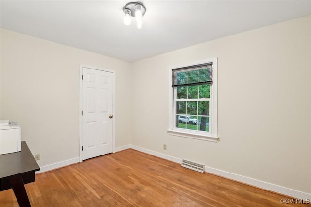 unfurnished room with light wood-type flooring and baseboards