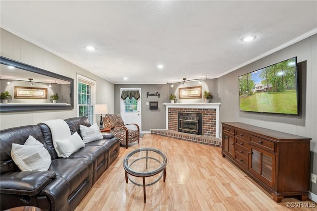 living room with light wood-style flooring, ornamental molding, recessed lighting, a brick fireplace, and baseboards