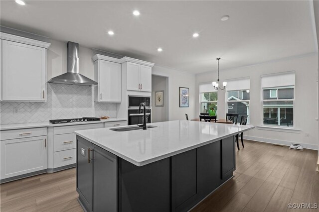9975 Honeybee Dr, Mechanicsville, VA 23116 - kitchen featuring wall chimney range hood, gas cooktop, stainless steel microwave, white cabinetry, and a kitchen island with sink