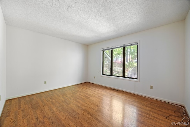 unfurnished room featuring wood finished floors, a textured ceiling, and baseboards