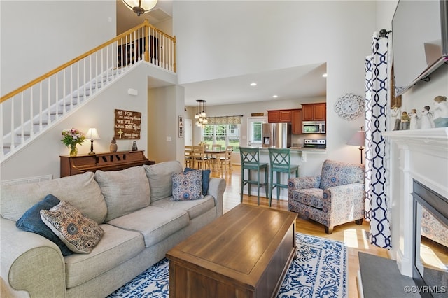 10335 Deerlake Dr, New Kent, VA 23124 - living room with stairs, a towering ceiling, light wood-style floors, a fireplace with flush hearth, and recessed lighting