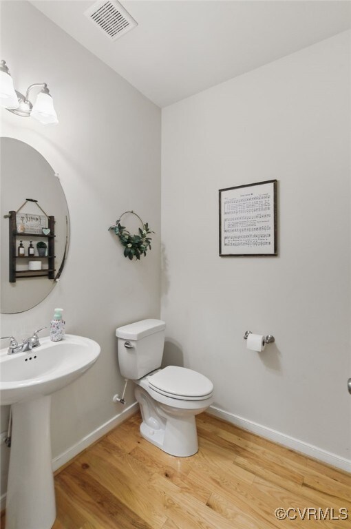 10335 Deerlake Dr, New Kent, VA 23124 - half bath with wood finished floors, toilet, baseboards, and a sink