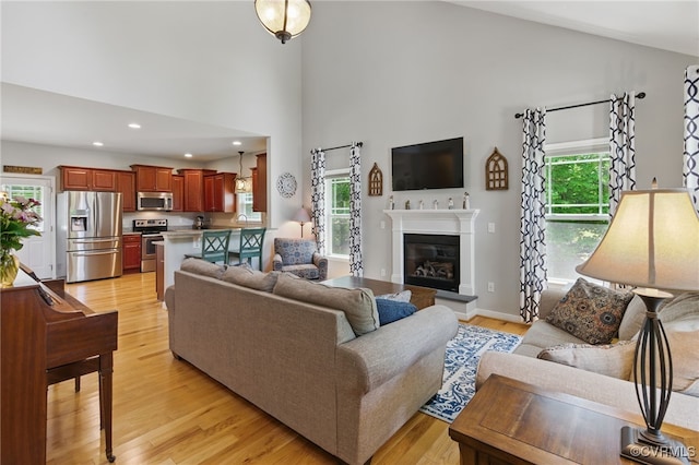 10335 Deerlake Dr, New Kent, VA 23124 - living area with light wood-style floors, high vaulted ceiling, a glass covered fireplace, and recessed lighting
