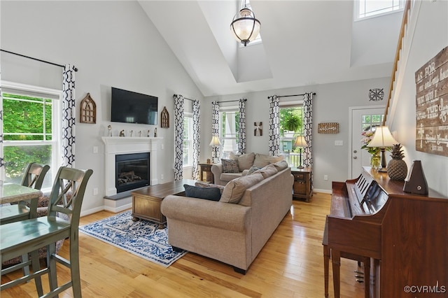 10335 Deerlake Dr, New Kent, VA 23124 - living room with light wood-type flooring, high vaulted ceiling, a glass covered fireplace, and baseboards