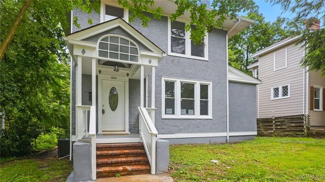 view of front of property featuring stucco siding, a front yard, and central AC unit