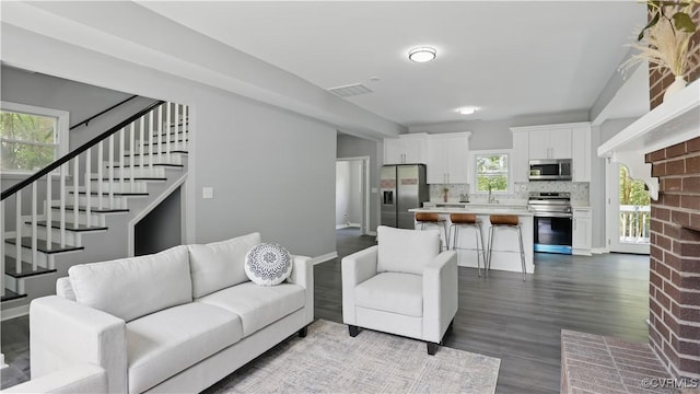 living area with stairway and dark wood-style flooring