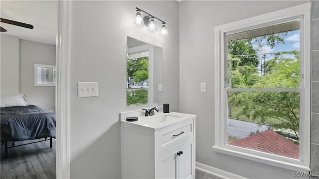 bathroom with vanity, healthy amount of natural light, baseboards, and a ceiling fan