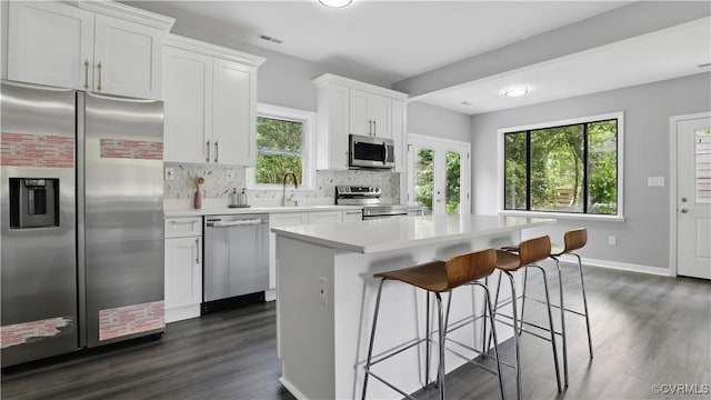 kitchen with stainless steel appliances, a kitchen island, tasteful backsplash, and dark wood-type flooring