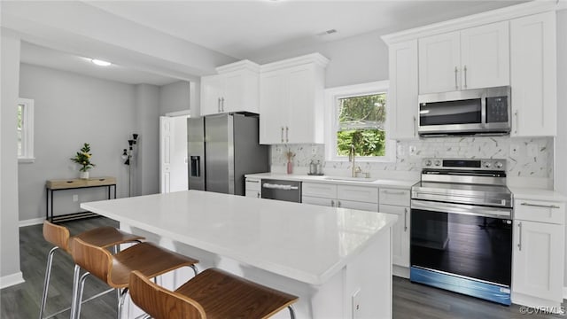 kitchen with stainless steel appliances, a sink, dark wood-style floors, decorative backsplash, and light countertops