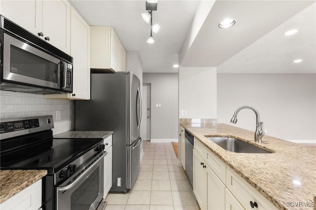 kitchen with stainless steel appliances, a sink, backsplash, light tile patterned floors, and light stone countertops