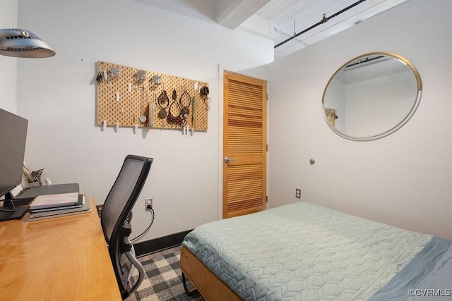 bedroom with beam ceiling, a desk, a closet, and baseboards