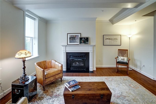 living room featuring wood finished floors, ornamental molding, a fireplace with flush hearth, and baseboards