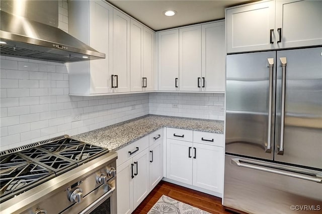 kitchen featuring appliances with stainless steel finishes, wall chimney range hood, white cabinets, and recessed lighting
