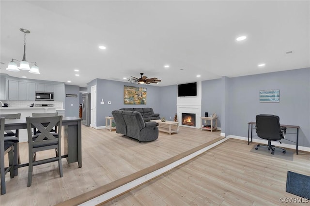 686 Shore Dr, Hartfield, VA 23071 - living area with a warm lit fireplace, baseboards, recessed lighting, ceiling fan, and light wood-style floors