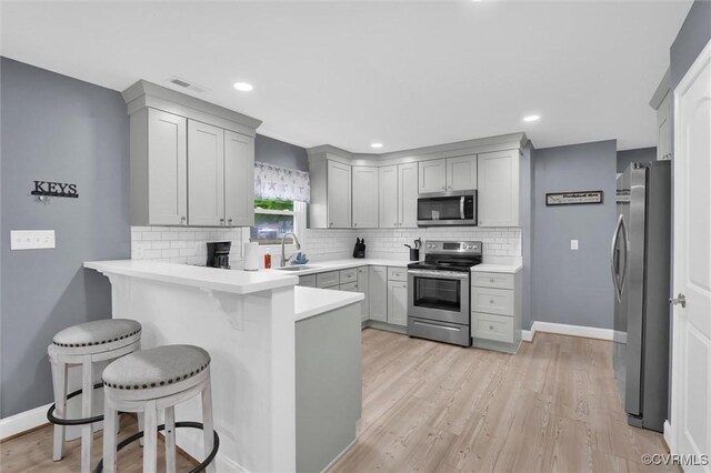 686 Shore Dr, Hartfield, VA 23071 - kitchen with stainless steel appliances, a peninsula, a sink, tasteful backsplash, and gray cabinets