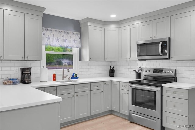 686 Shore Dr, Hartfield, VA 23071 - kitchen featuring appliances with stainless steel finishes, a sink, gray cabinets, light countertops, and tasteful backsplash