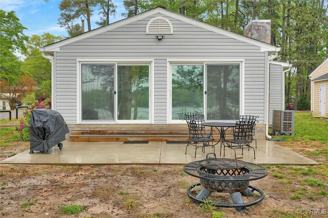 686 Shore Dr, Hartfield, VA 23071 - back of property with an outdoor fire pit, a patio, a chimney, and central AC