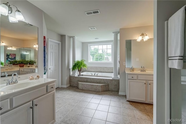 bathroom with decorative columns, a bath, tile patterned floors, and two vanities