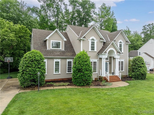 traditional-style home with a front lawn and roof with shingles