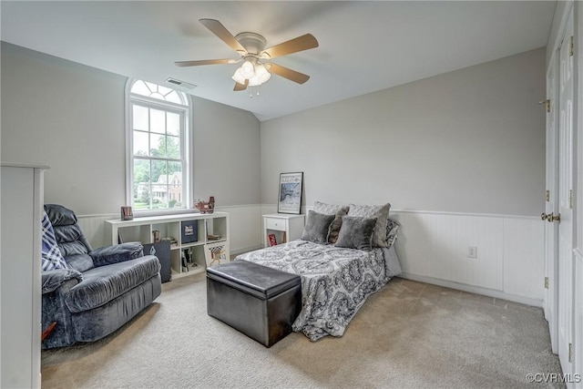 carpeted bedroom featuring a wainscoted wall and ceiling fan